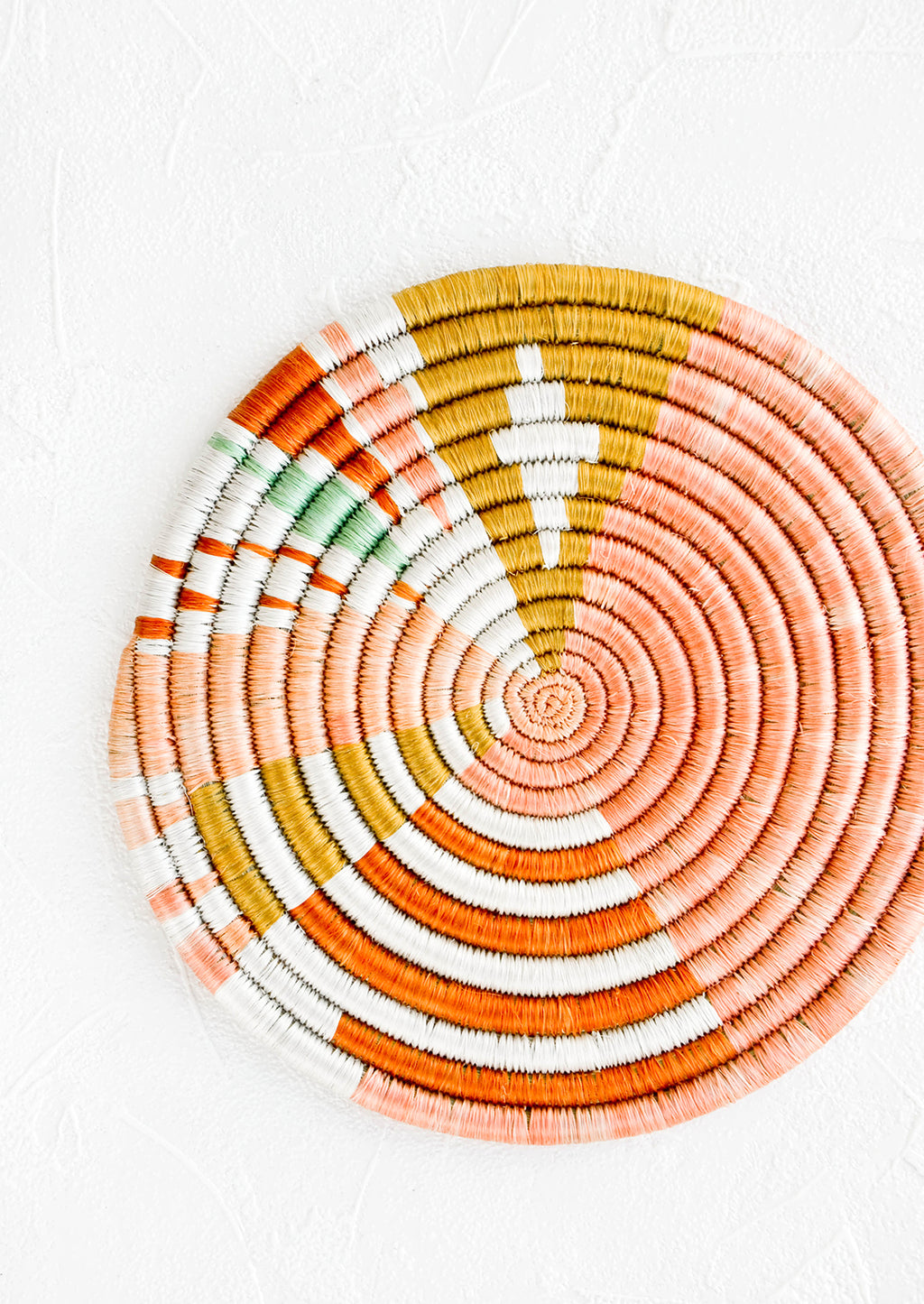 1: Colorful round trivet made from dyed raffia in a geometric pattern and pastel hues