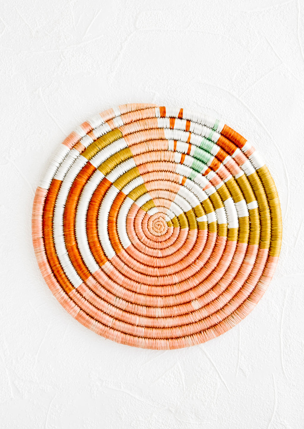 2: Colorful round trivet made from dyed raffia in a geometric pattern and pastel hues