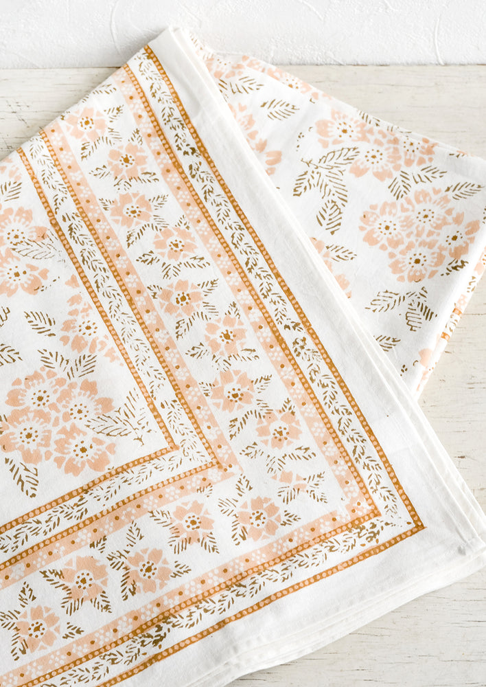 1: A block printed tablecloth with peach and brown floral print.