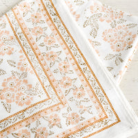 1: A block printed tablecloth with peach and brown floral print.