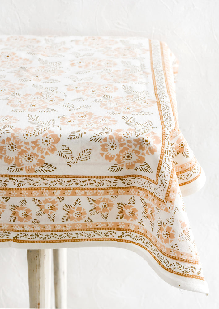 2: A block printed tablecloth with peach and brown floral print.