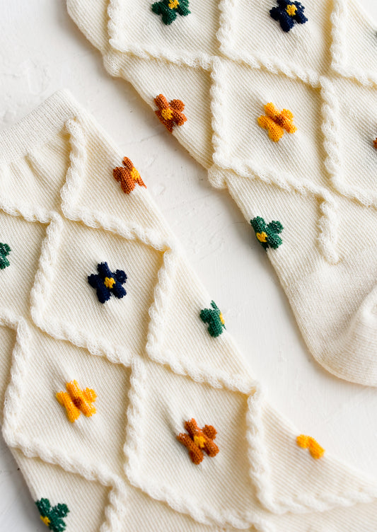 A pair of cream socks with diamond pattern and florals.