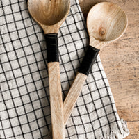 1: A pair of wooden salad servers with decorative black wire wrapping on handle.