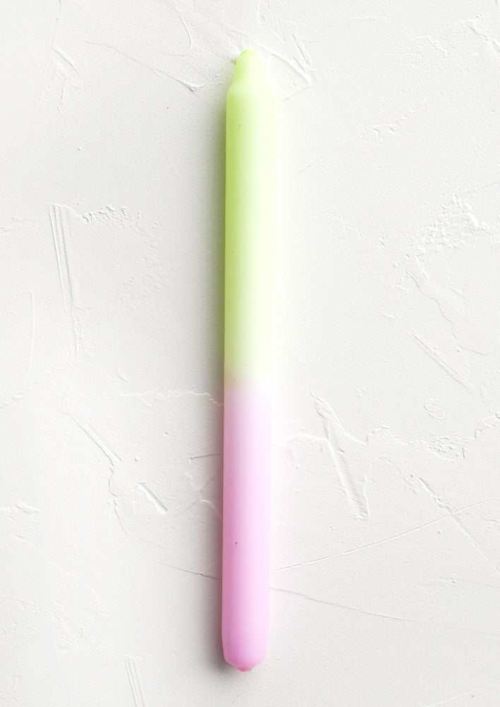 A straight taper candle in neon yellow and pink.