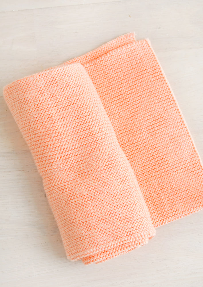 A knit cotton dish towel in papaya pink.