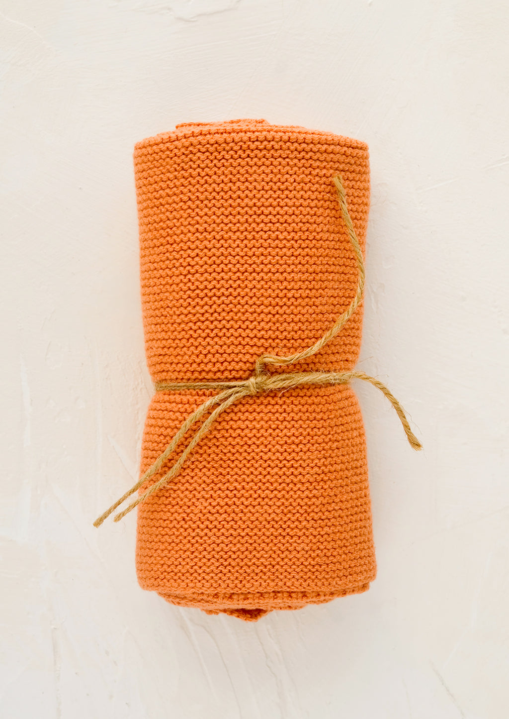 Terracotta: A knit cotton dish towel in terracotta, rolled and tied with twine.