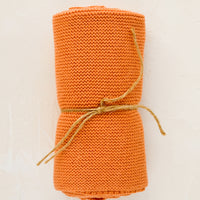 Terracotta: A knit cotton dish towel in terracotta, rolled and tied with twine.