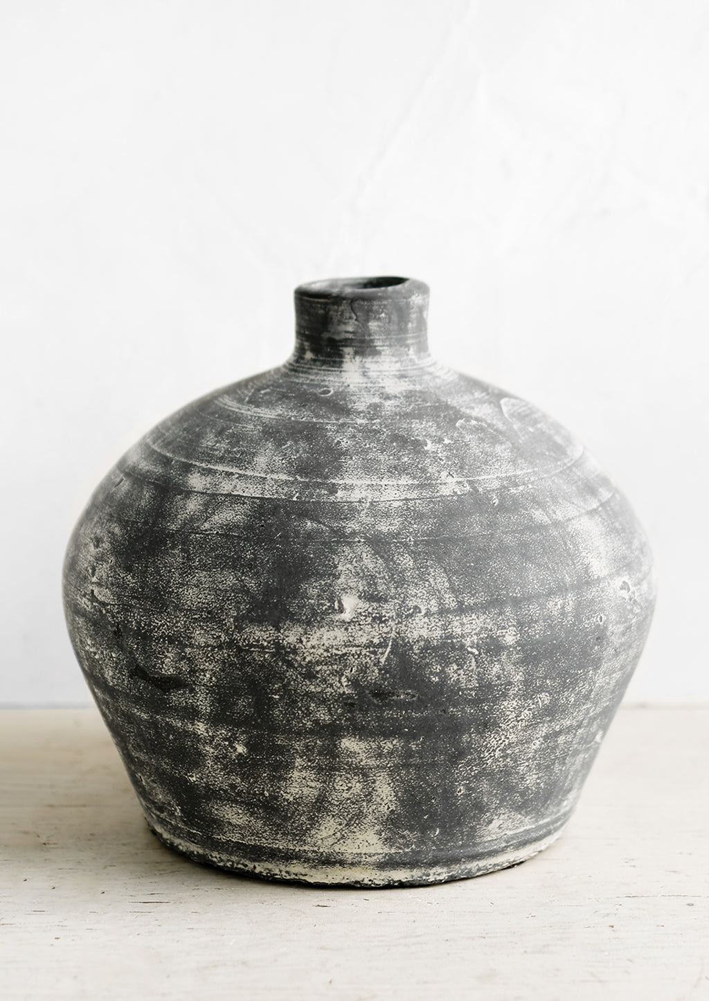 2: A distressed black clay vase with narrow opening.