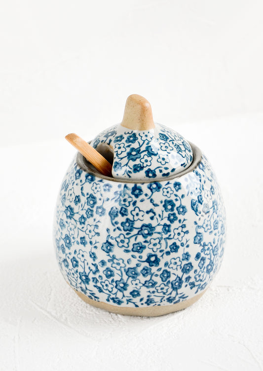 A lidded sugar jar with included spoon made of ceramic in grey with blue ditsy floral print.
