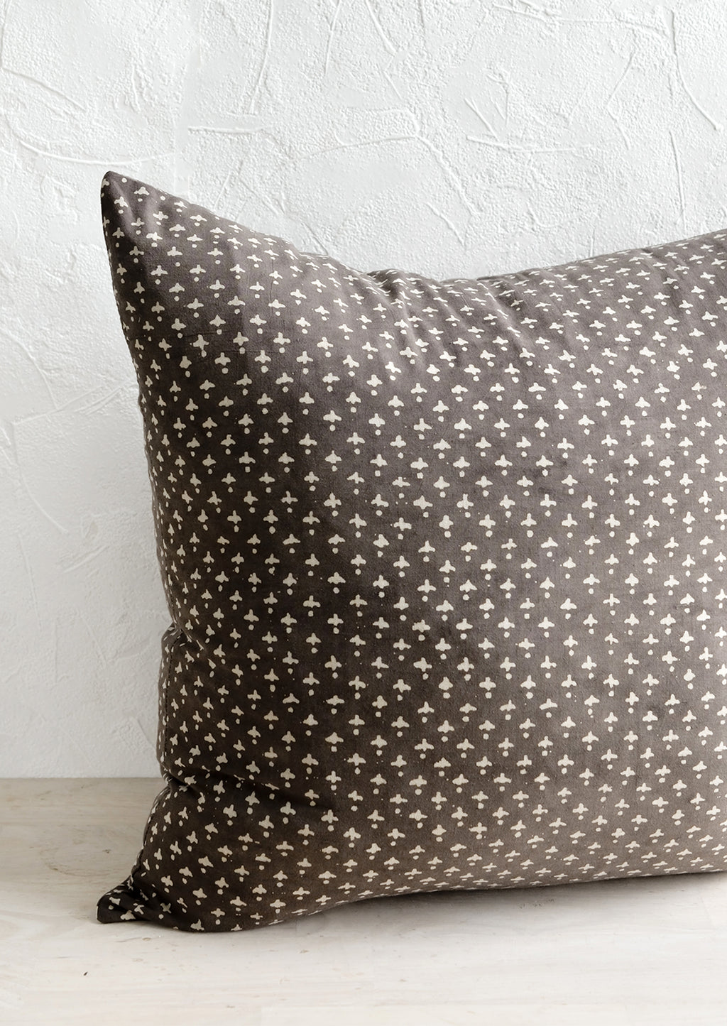 1: A square block printed throw pillow in dark grey with white dot-cross motif.
