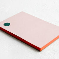 2: A pink notepad with green dot at top left corner and red painted edges.