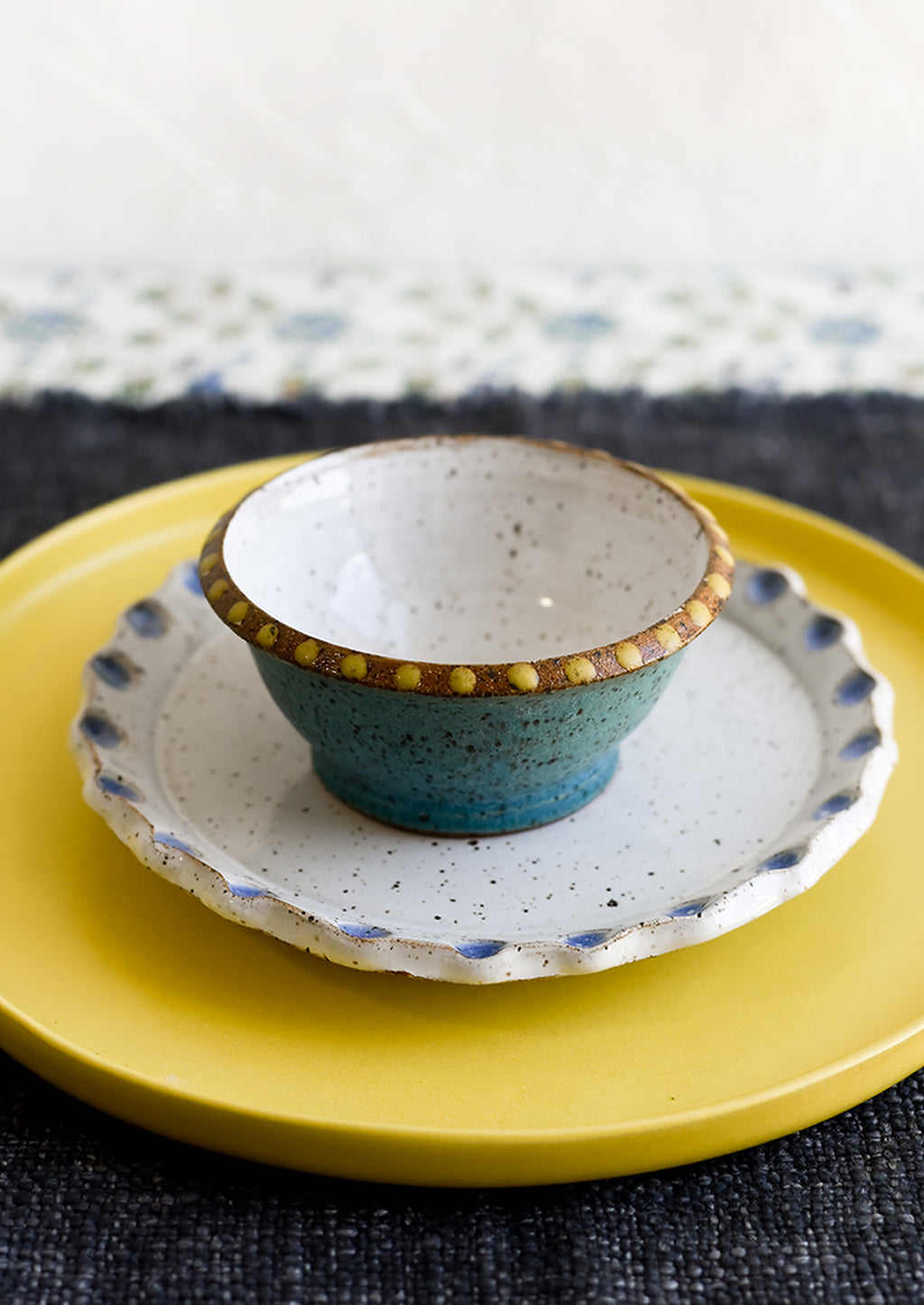 3: A small turquoise ceramic bowl with yellow dot painted detailing.