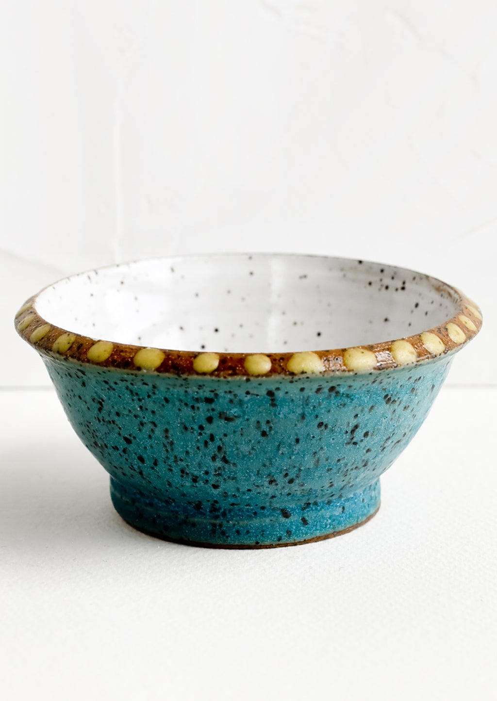 Galapagos / Ochre: A small turquoise ceramic bowl with yellow dot painted detailing.