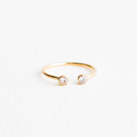 Clear Crystal / Size 6: Yellow gold adjustable ring with opening at front and yellow stone on each side of the opening.
