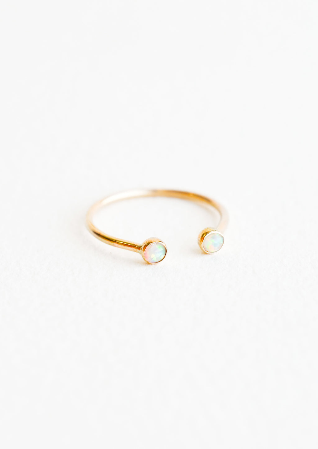Opal / Size 6: Yellow gold adjustable ring with opening at front and an opal stone on each side of the opening.