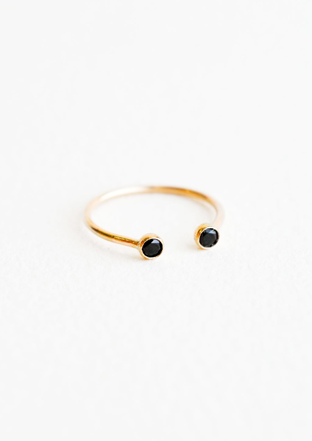 Black Spinel / Size 6: Yellow gold adjustable ring with opening at front and a black stone on each side of the opening.