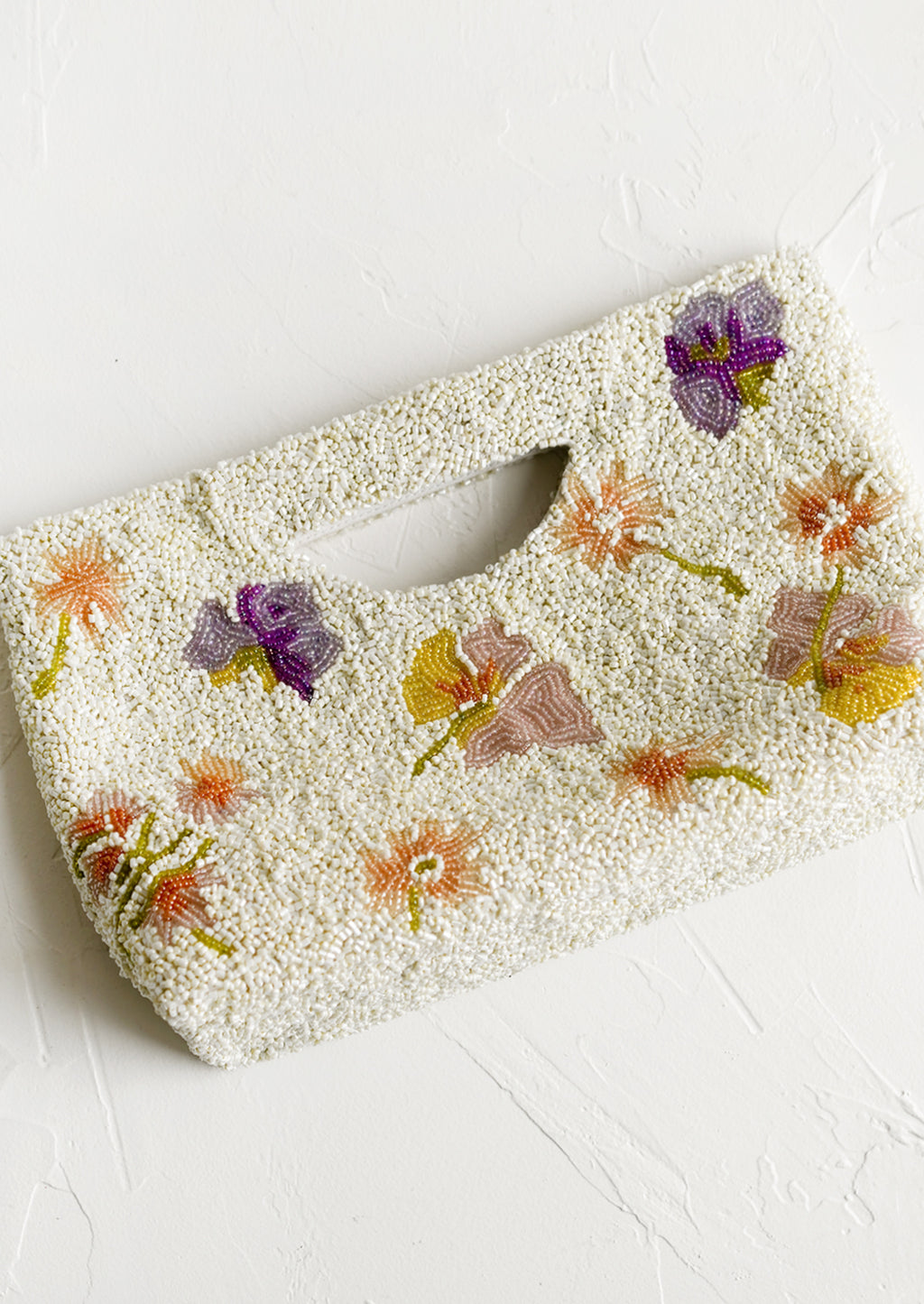 3: A white beaded east-west clutch with cutout handle and pastel floral pattern.