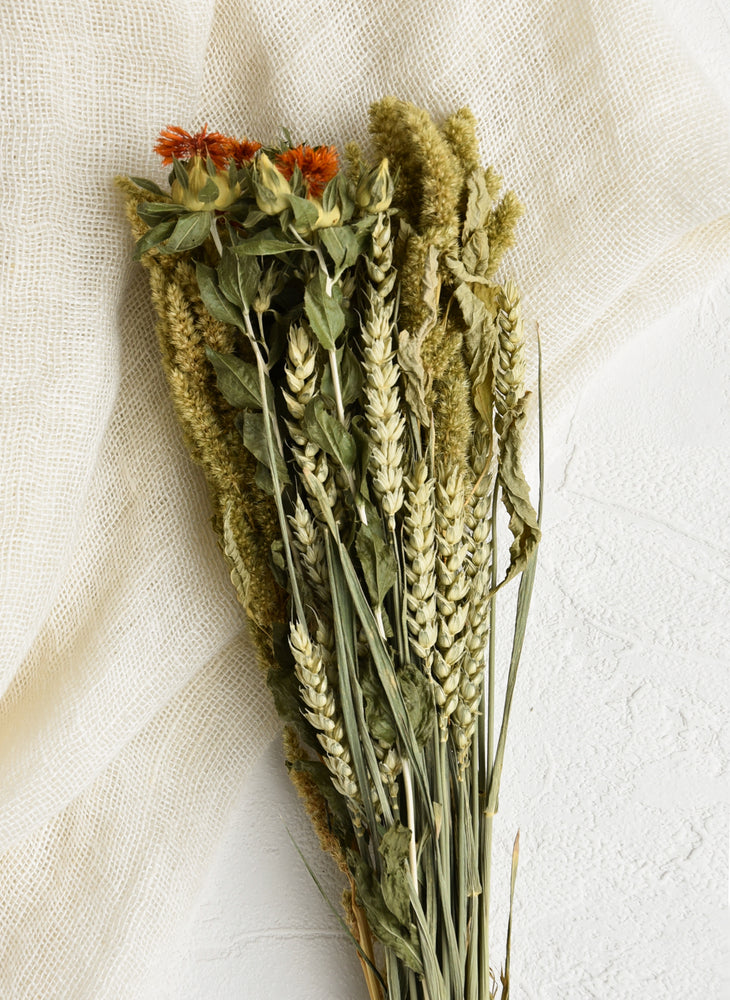 A bouquet of dried greenery with wheat and a few pops of orange
