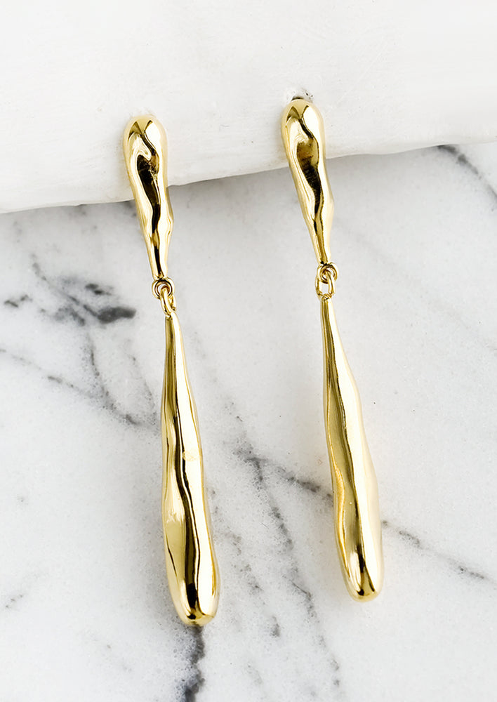 A pair of gold earrings with two-part melty drip shape.
