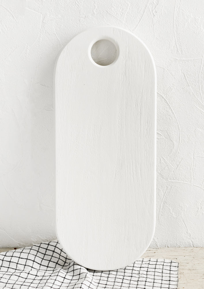 A long oval shaped wooden board with white wood finish.