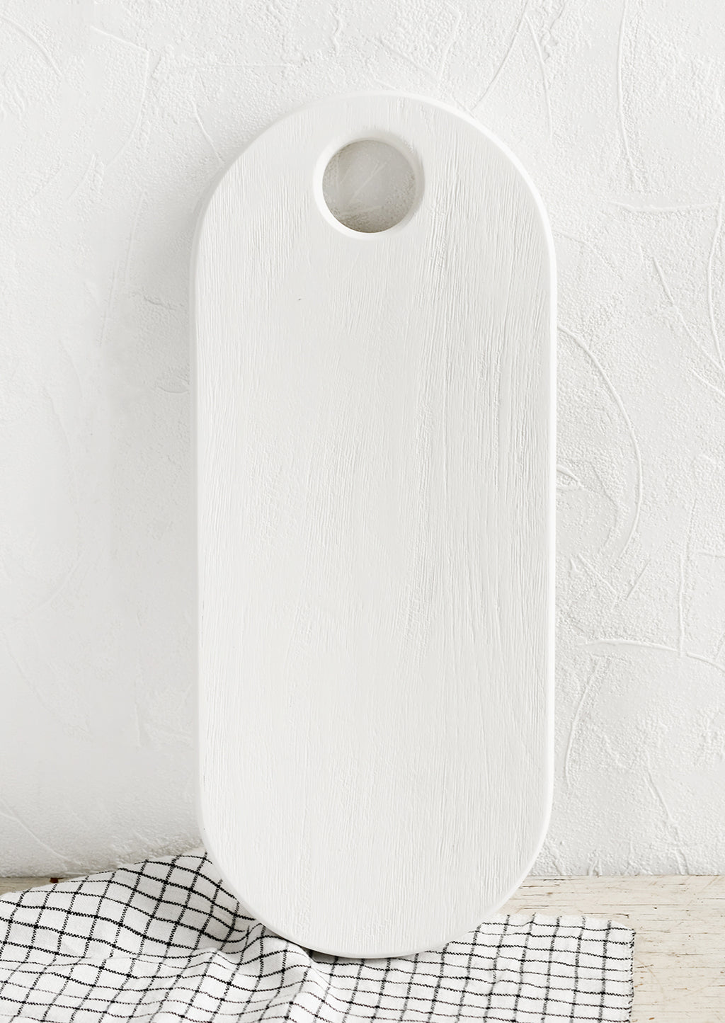 2: A long oval shaped wooden board with white wood finish.
