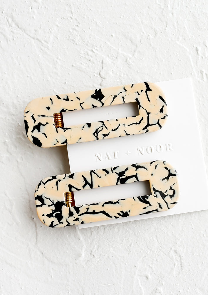 A pair of open rectangle shaped acetate hair clips in tan and black marble.