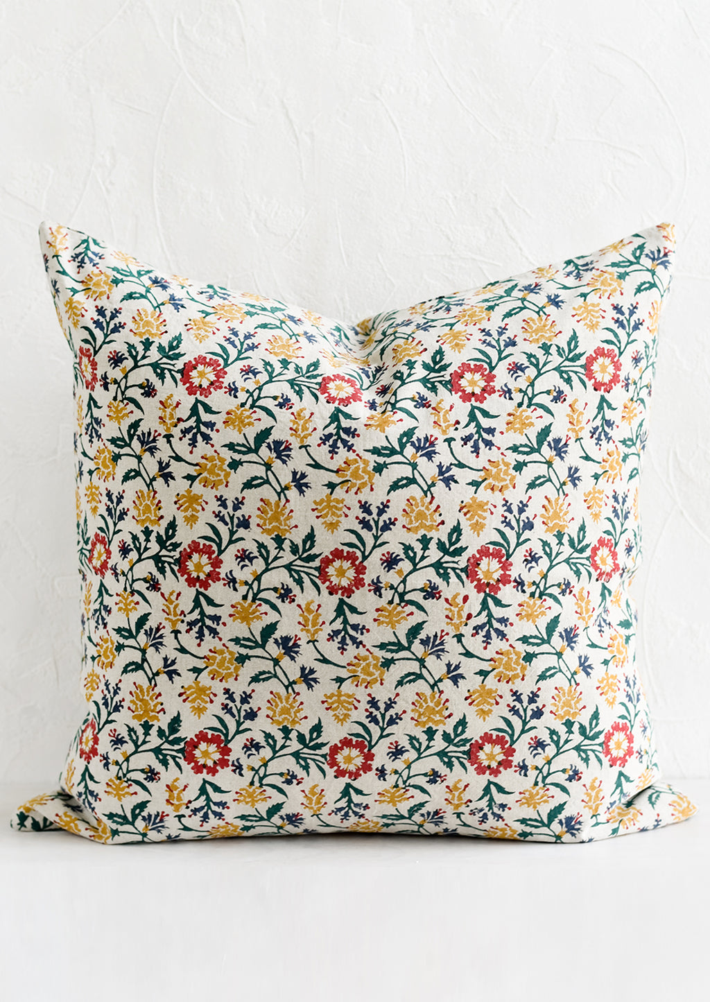 1: A block printed pillow in green, red, blue and yellow floral print.