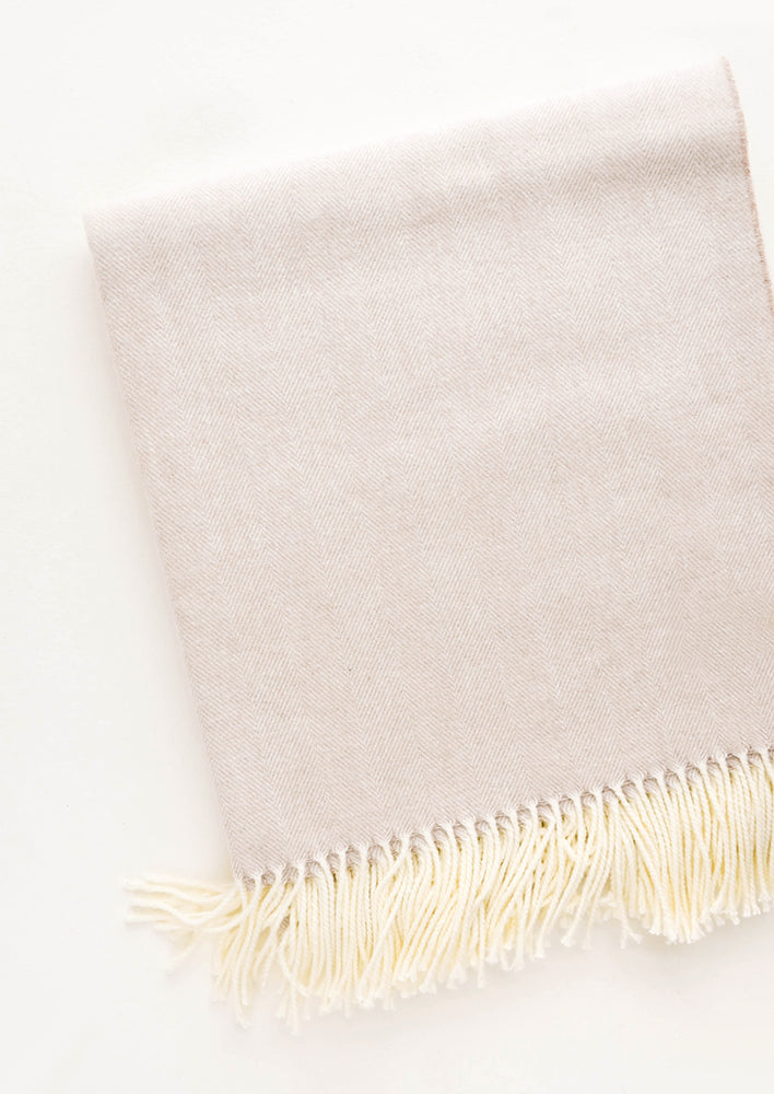 Soft throw blanket in fine herringbone weave and ivory tassel trim. Soft tan color.