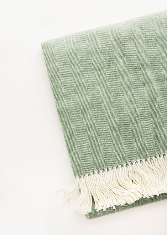 Green throw blanket in fine herringbone weave and ivory tassel trim