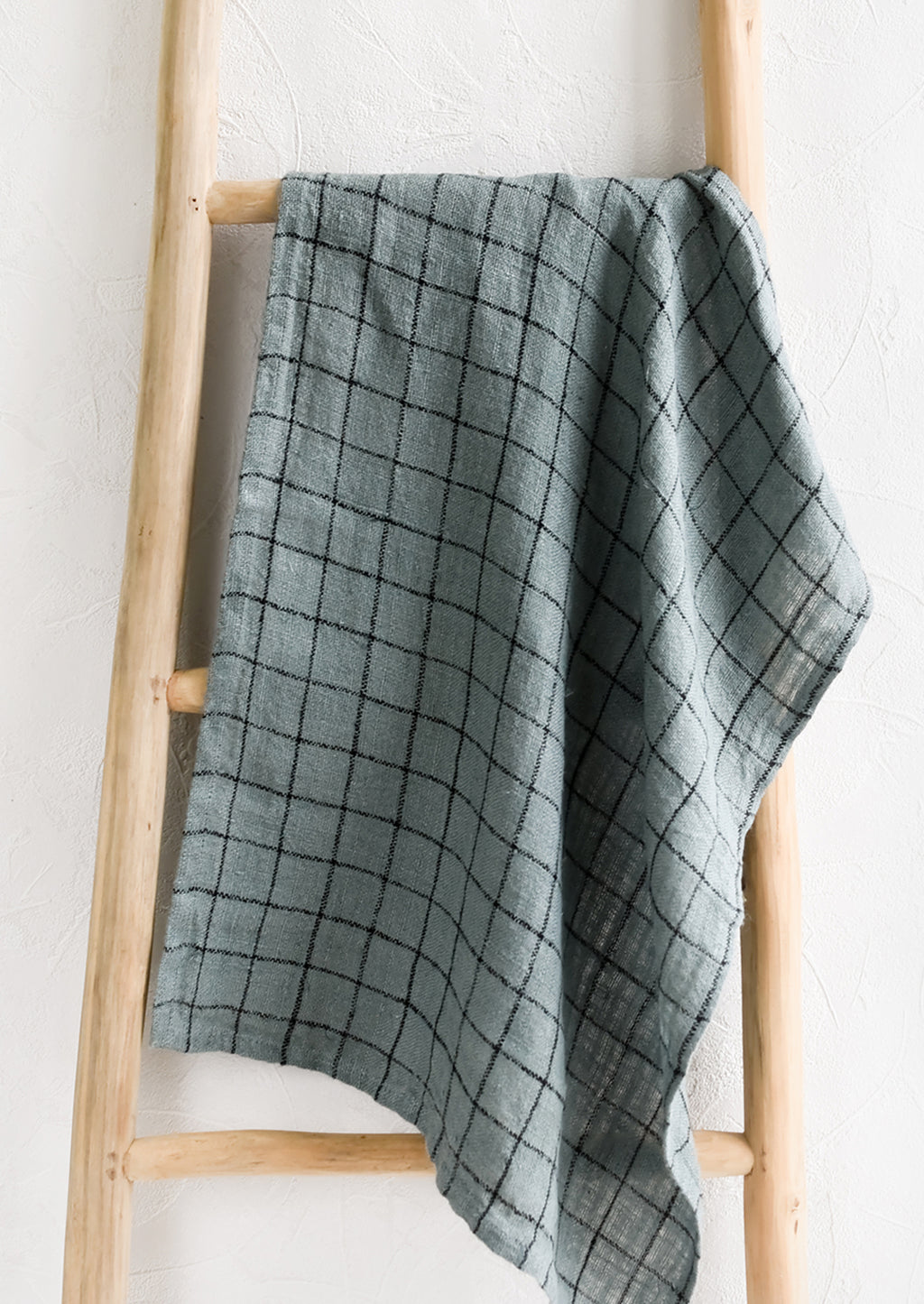 Dusty Blue: A woven tea towel in dusty blue with black grid pattern.