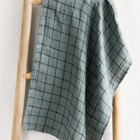 Dusty Blue: A woven tea towel in dusty blue with black grid pattern.