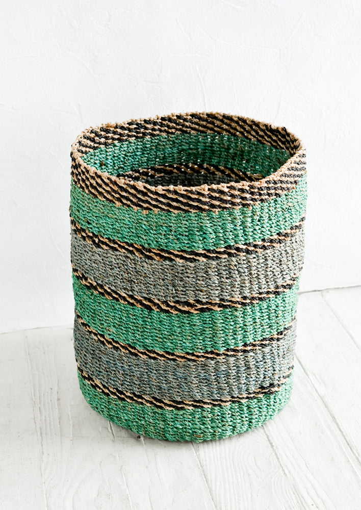 A medium woven straw storage basket in a turquoise and blue stripe print.