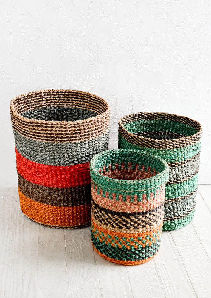 Three woven storage baskets in incremental sizes and different colored striped patterns.