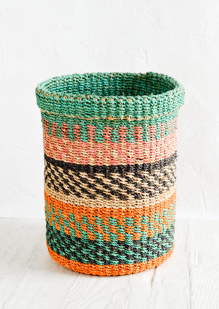 A small woven straw storage basket in a colorful stripe print.