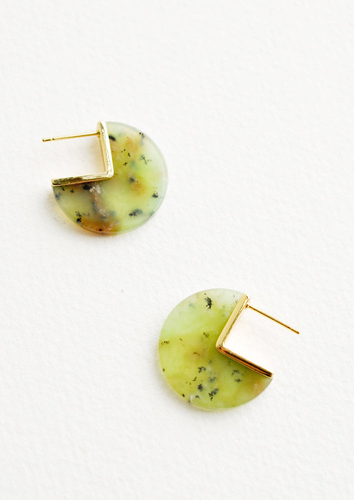 Three quarter disc shaped earrings of a yellow-green gemstone speckled with brown flecks with gold hardware and post back.