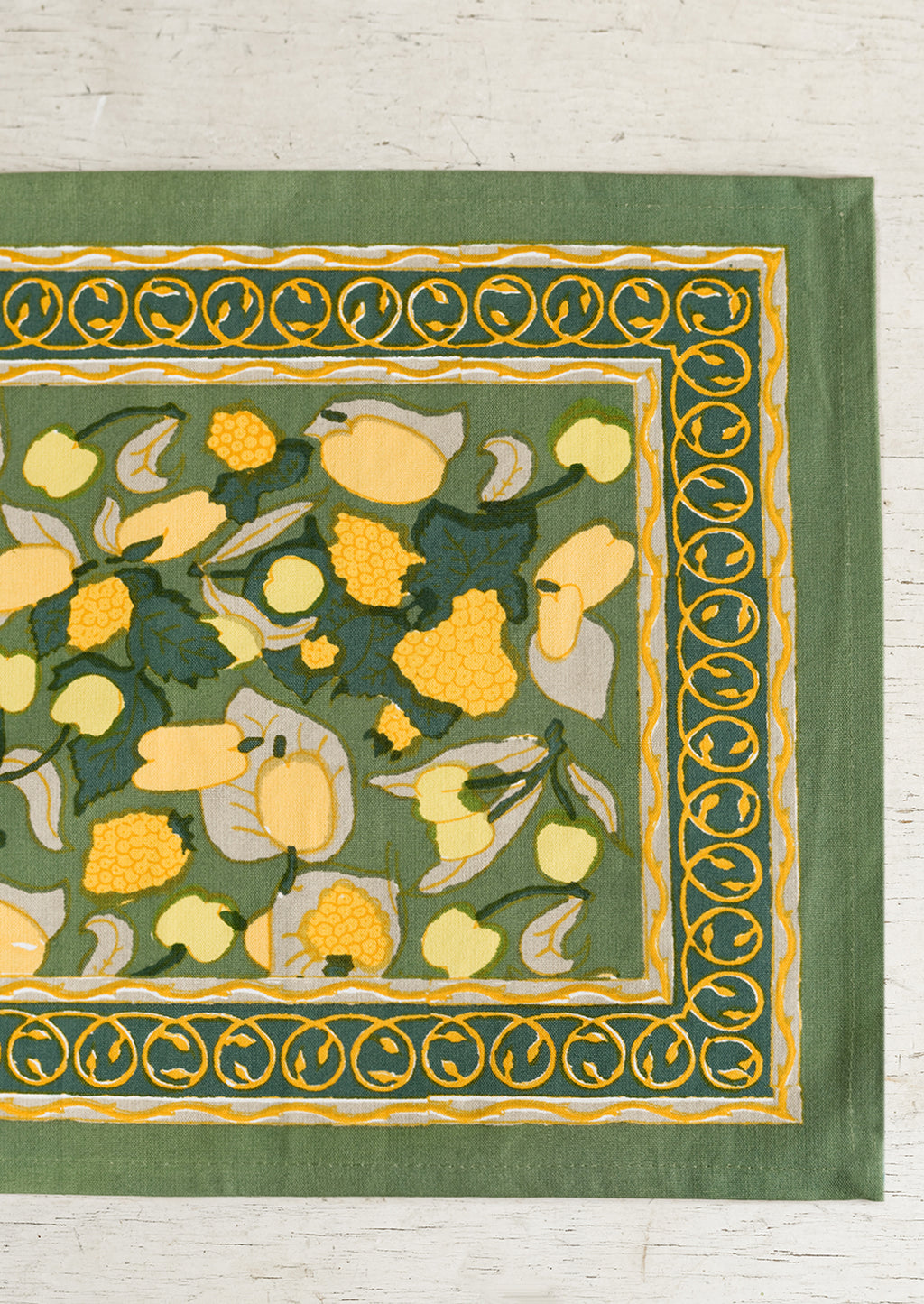 1: A block printed placemat in green and yellow fruit print.