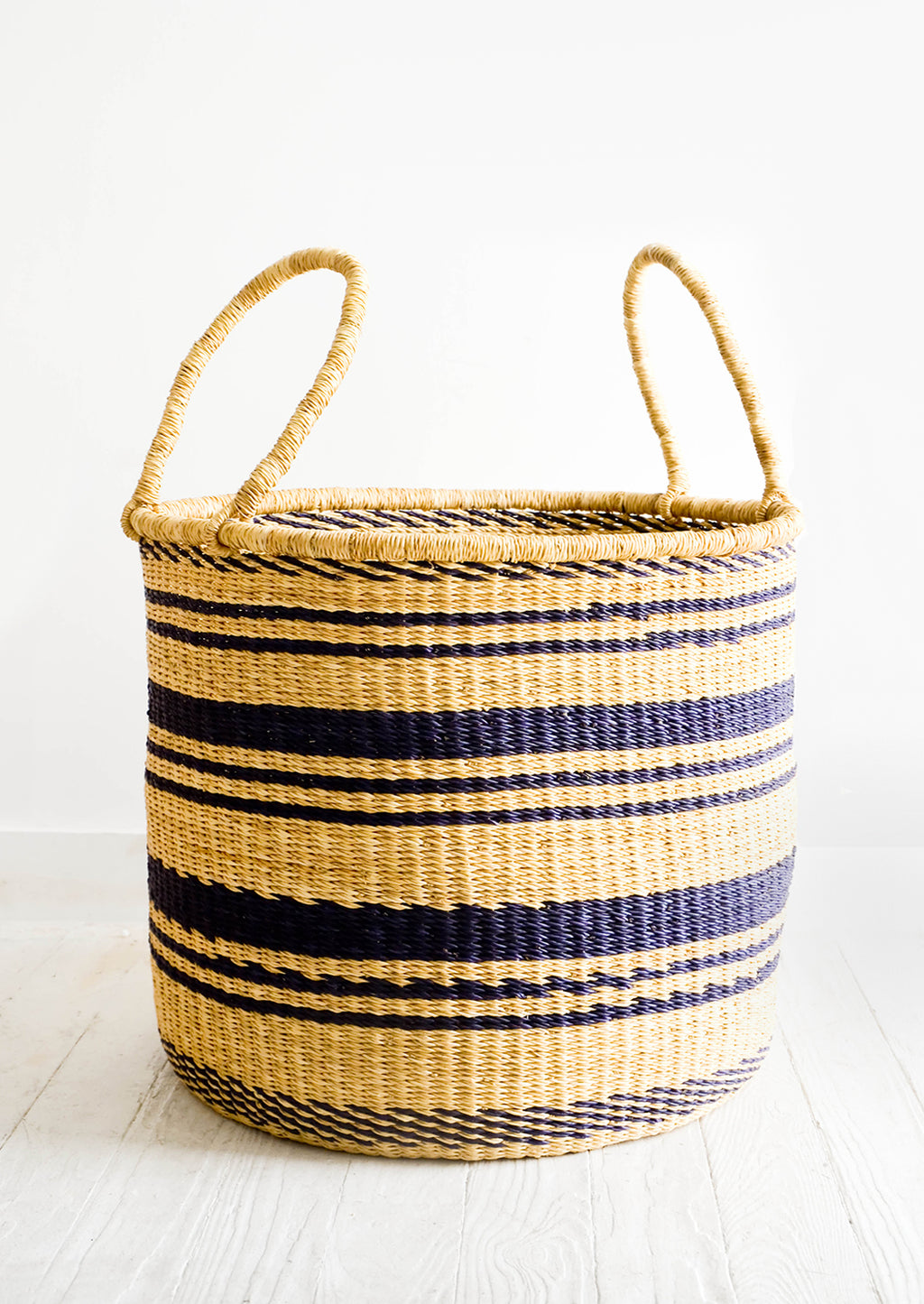 Large: Round straw storage basket with handles at top and navy blue stripes throughout