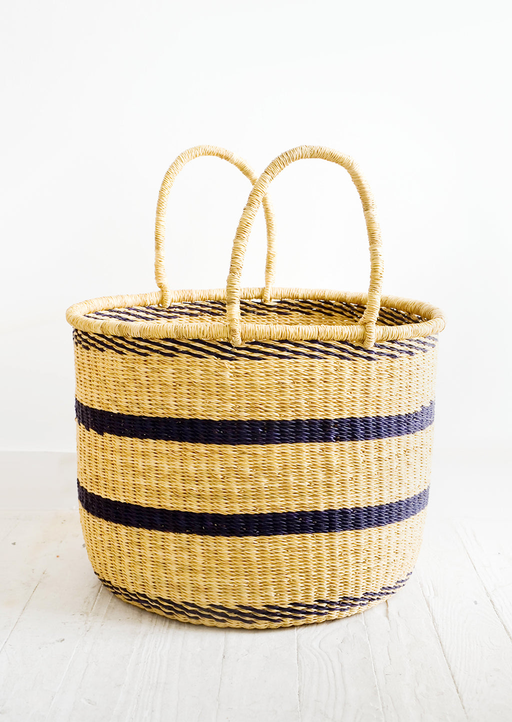 Medium: Round straw storage basket with handles at top and navy blue stripes throughout