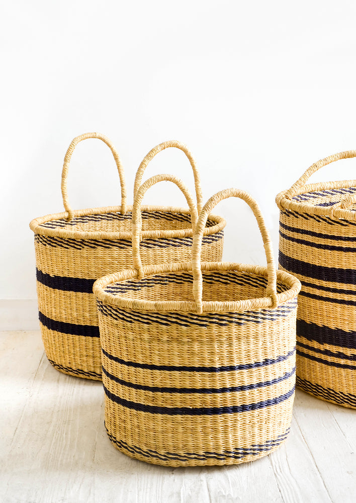 4: Group of round straw storage baskets with handles at top and navy blue stripes throughout