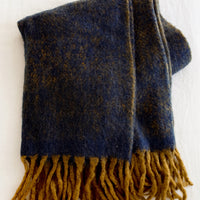 1: A fuzzy mohair-like blanket in navy and mustard with mustard tassel trim.