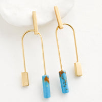Gold / Turquoise: A pair of gold earrings with bar shaped top and arched bottom with turquoise gemstone on one side.