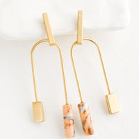 Gold / Peach Multi: A pair of gold earrings with bar shaped top and arched bottom with peach gemstone on one side.