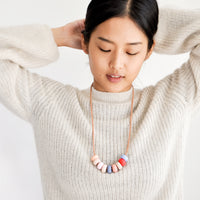 3: Model wears clay bead necklace and ivory sweater.