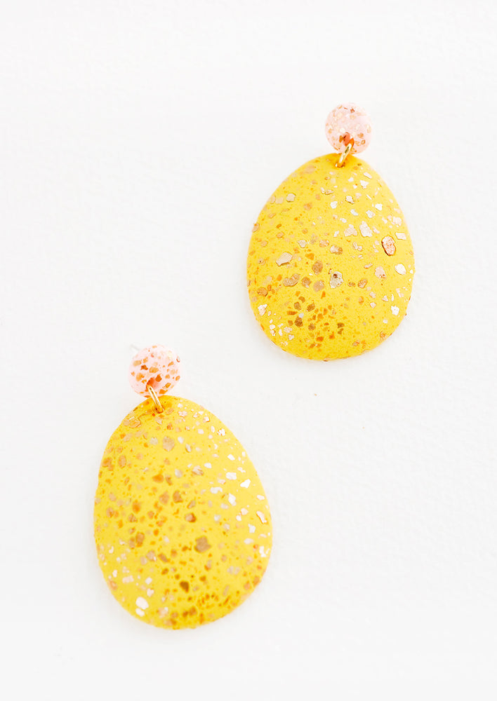 Dangling glitter covered earrings, with a yellow larger oval dangling from a small pink bead.