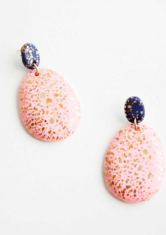 Dangling glitter covered earrings, with a peach larger oval dangling from a small dark bead.