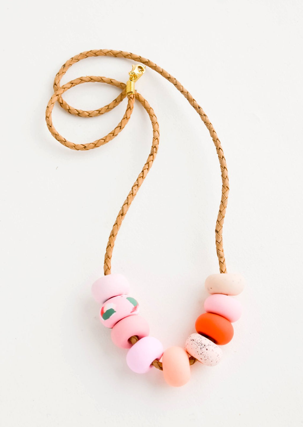 1: Necklace made from round clay beads in pink hues strung on braided leather cord