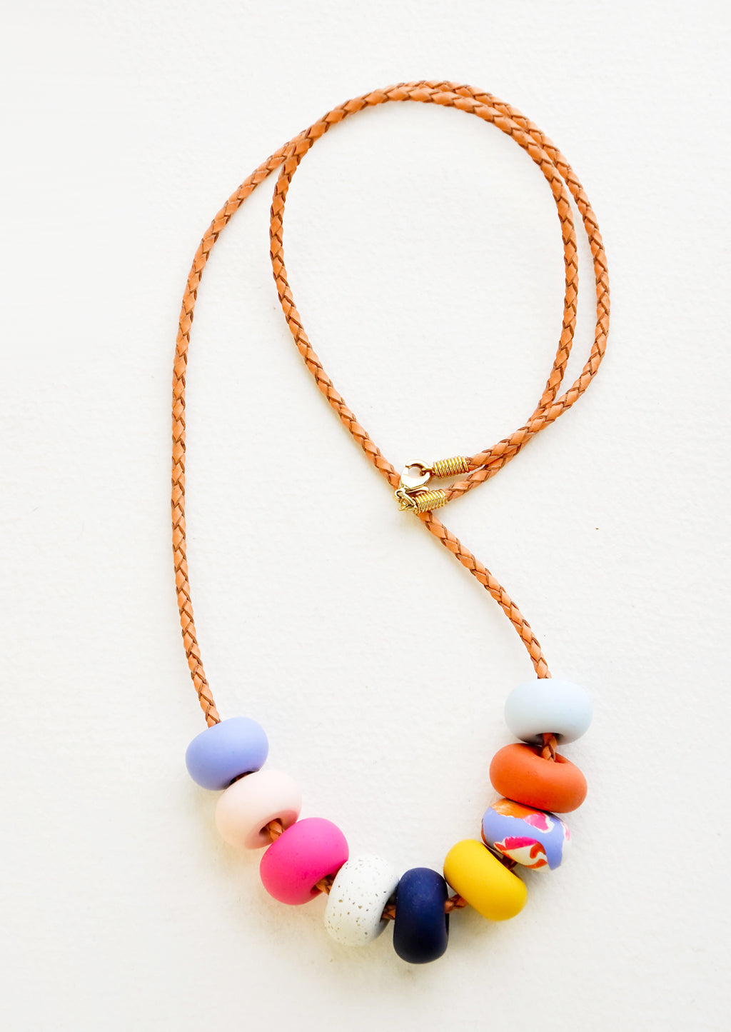 9 Bead: Necklace with gold clasp, brown woven leather cord, and nine multi-colored clay beads in blues, pinks, yellows, and oranges. 