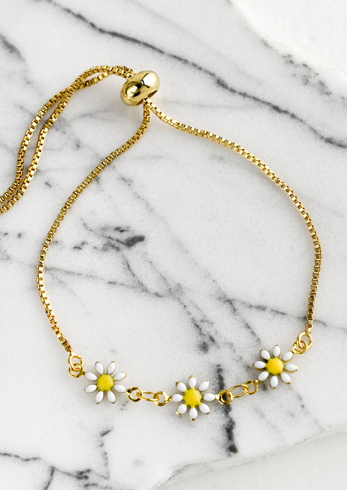 A gold bracelet with three white and yellow enamel daisies.