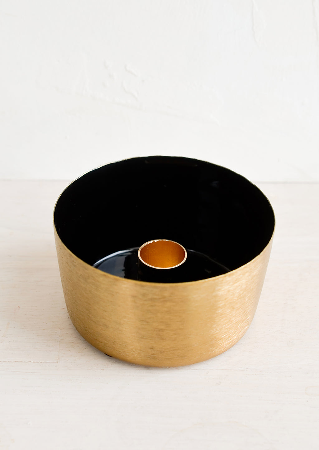 Black: A round brass taper holder with high walls and black enamel lining.