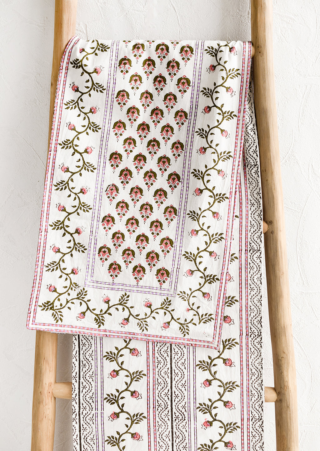 2: A block printed white table runner with pink, green and lavender floral print.